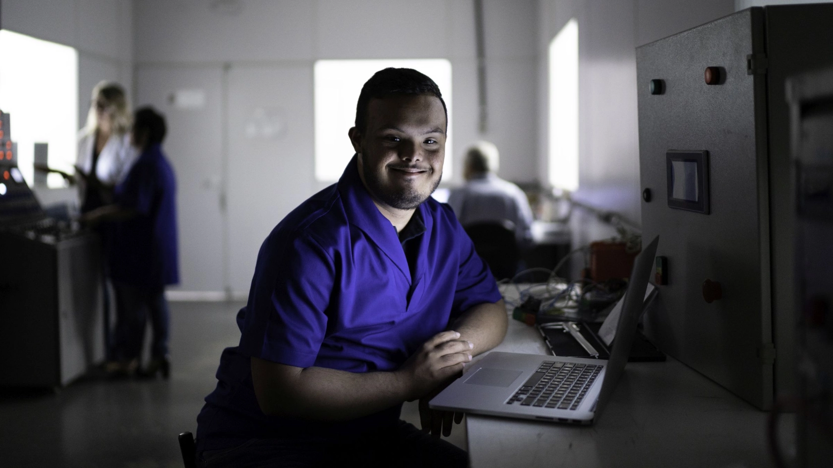 Mensch mit Behinderg arbeitet am Notebook