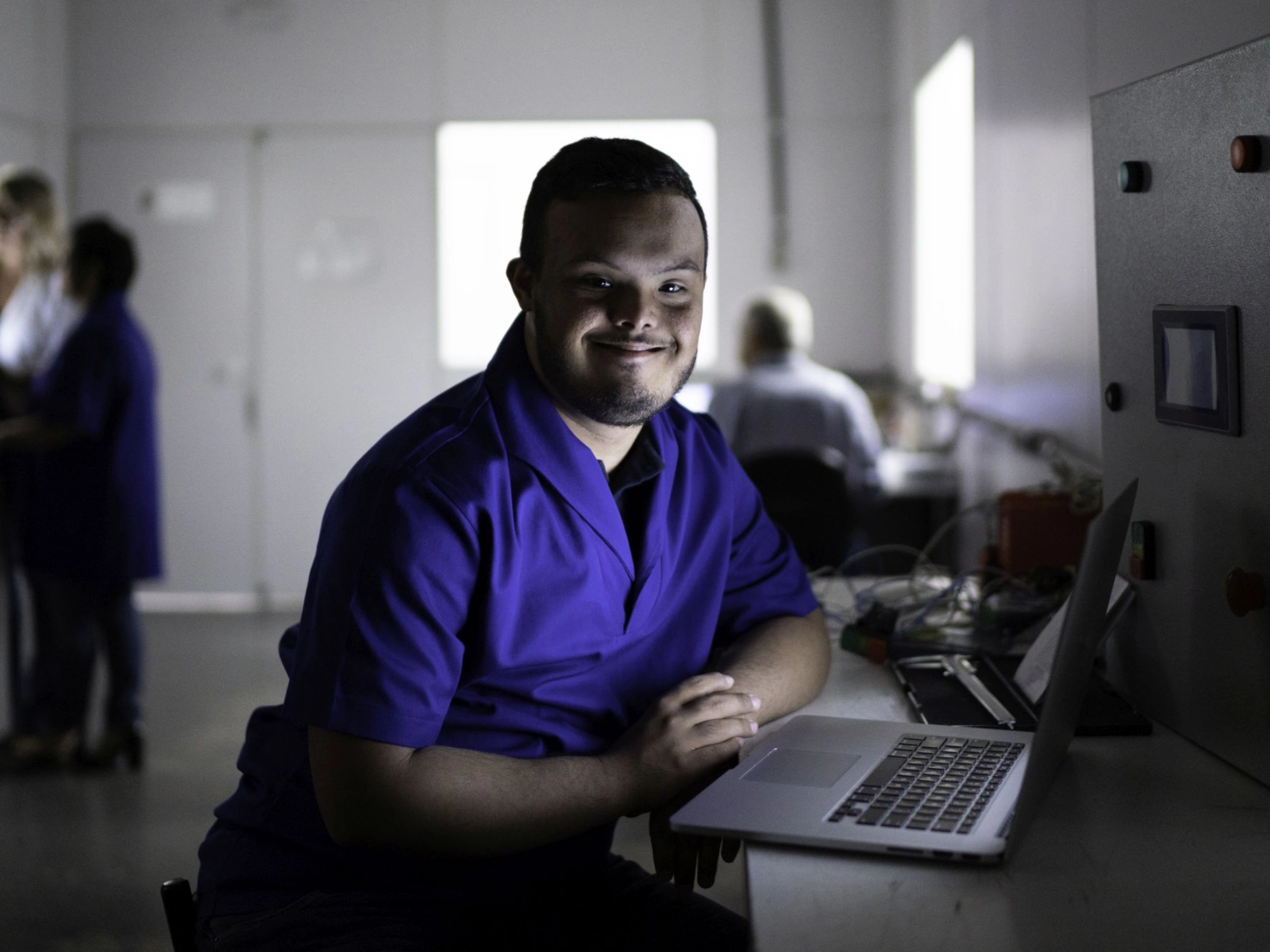 Mensch mit Behinderg arbeitet am Notebook