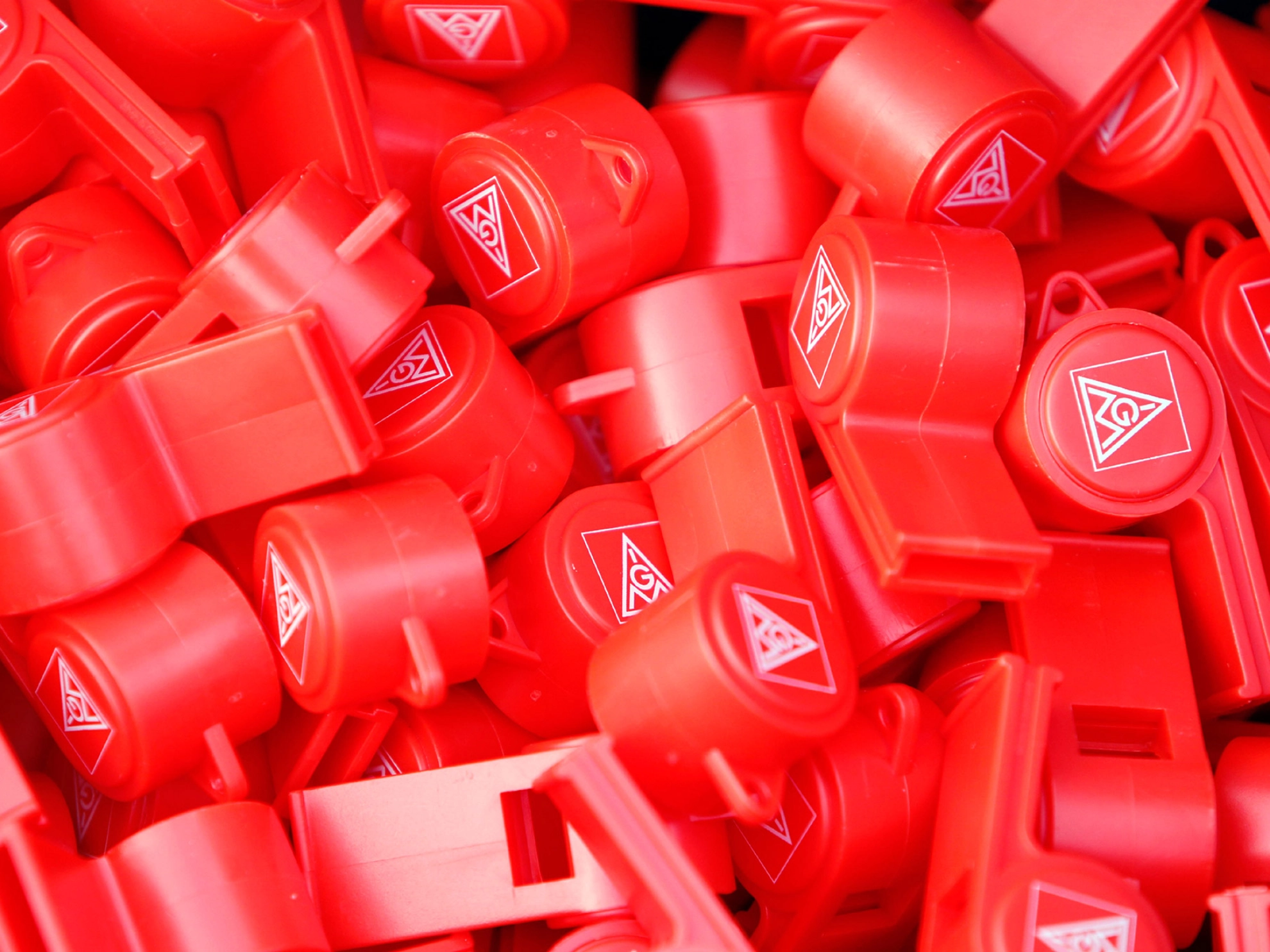 Viele rote Trillerpfeifen mit dem Logo der IG Metall.