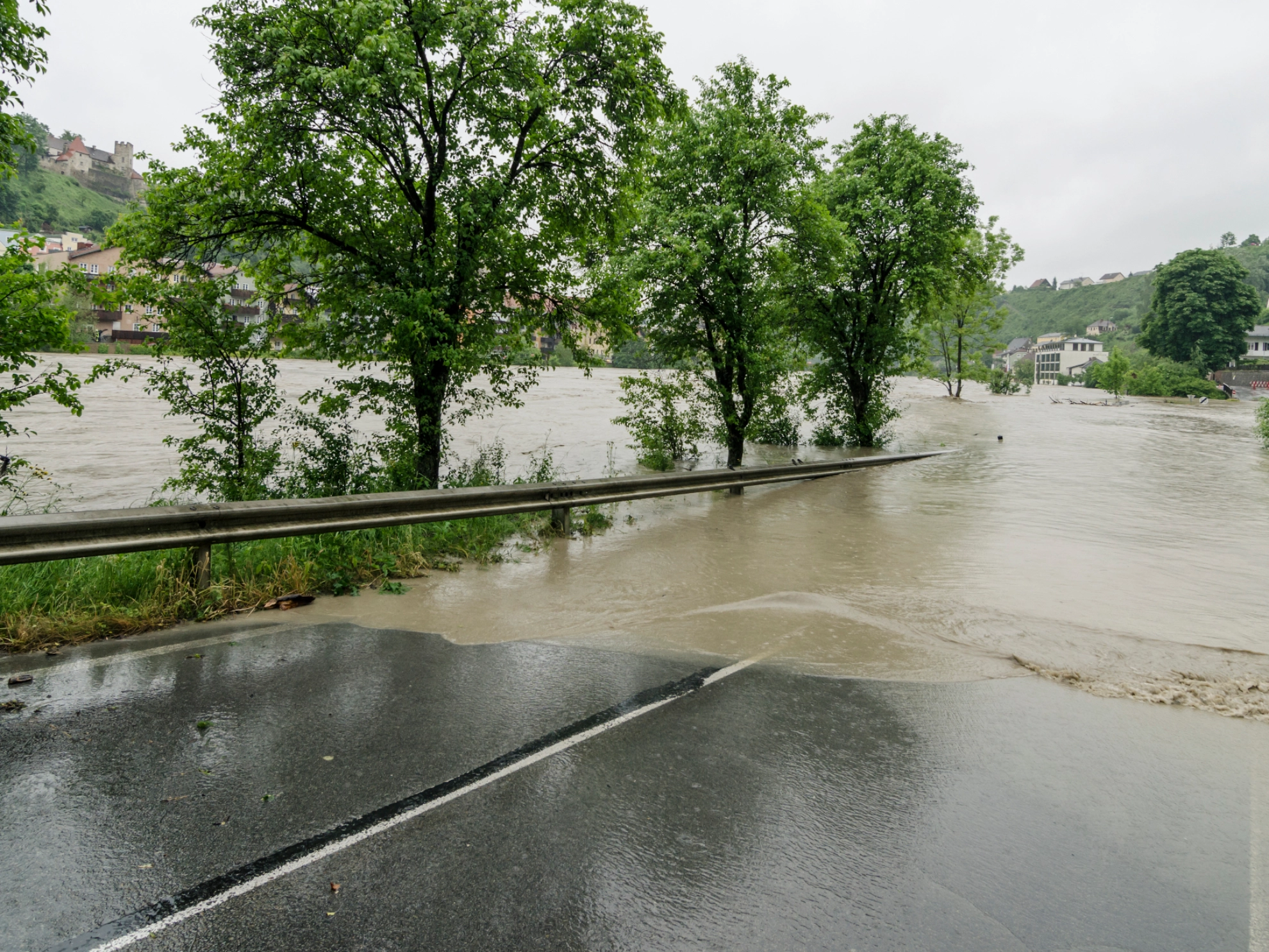 Eine Überflutete Straße neben einem übertretenden Fluss.