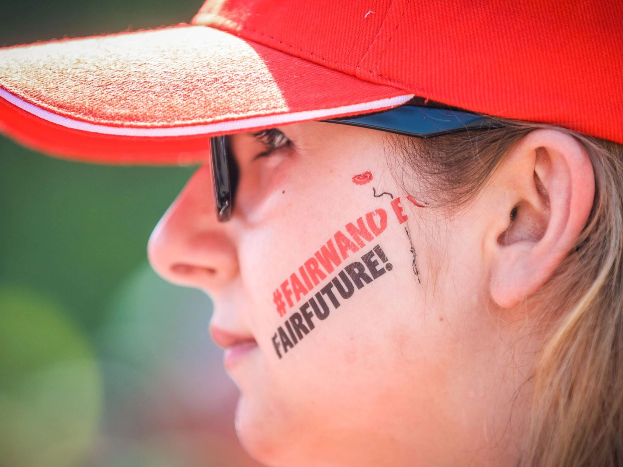 junge Metallerin trägt das Motto "FairWandel-FairFuture" aufgemalt auf ihrer Backe