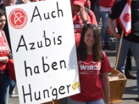 Junge Frau bei einem Warnstreik während der Tarifrunde mit einem Transparent mit der Aufschrift "Auch Azubis haben Hunger".