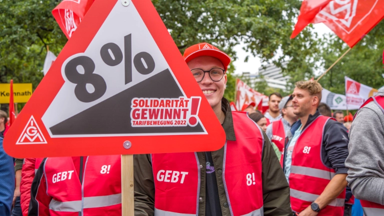 Junger Mann hält 8% Schild hoch